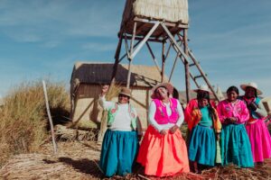 Mujeres de las Islas Flotantes de los Uros, Lago Titicaca, Perú. Vestidas con trajes tradicionales de colores brillantes, representan la cultura ancestral y la vida en las islas de totora